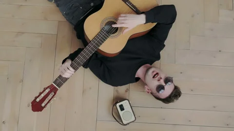 Unusual and authentic millennial guy try to escape boredom. He lying on the wood Stock Footage 107813484