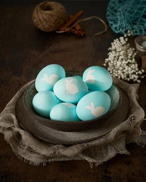 Unusual Easter on dark background. Ceramic brown bowl with blue eggs. Darkness Stock Photos