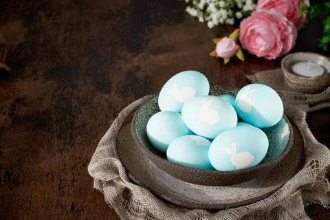 Unusual Easter on dark old background. Ceramic brown bowl with blue eggs. Stock Photos