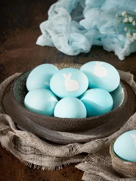 Unusual Easter on dark old background. Ceramic brown bowl with blue eggs Stock Photos
