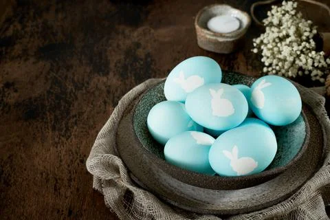 Unusual Easter on dark old background. Ceramic brown bowl with blue eggs. Stock Photos