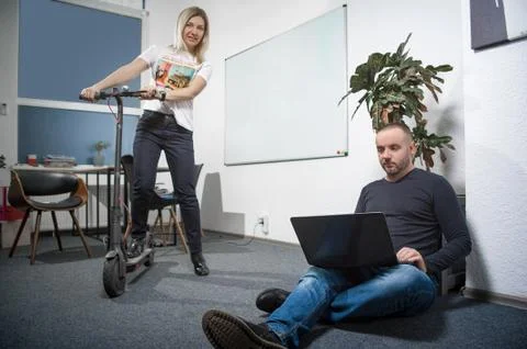 The unusual situation in the office, the guy at work and the girl on the scooter Stock Photos