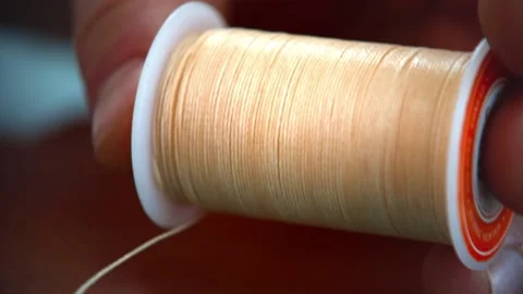 Unwinding a nylon thread close-up. Fingers hold a spool of nylon thread, slowly Video stock 132092701