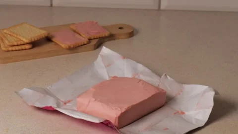 Unwrapped block of pink raspberry butter on countertop with cookies spread with Stock Footage 314012008