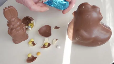 Unwrapping Blue Foil Easter Egg Amidst Assortment of Chocolate Treats Stock Footage 332943196