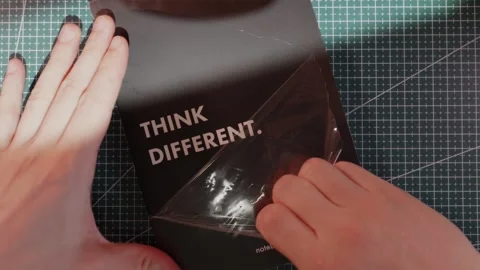 Unwrapping protective foil from Think Different notebook flat lay Stock Footage 340139260