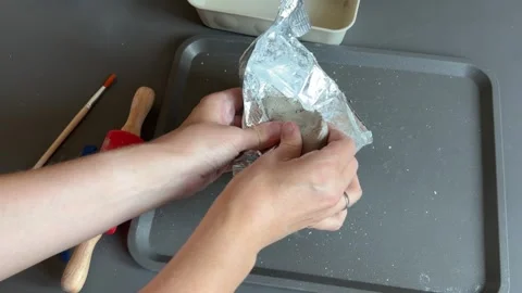 Unwrapping soft gray clay before making a seasonal pumpkin decoration Stock Footage 345719794