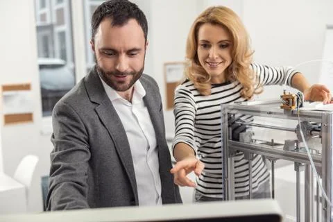 Upbeat colleagues setting parameters for 3D printer via computer Stock Photos