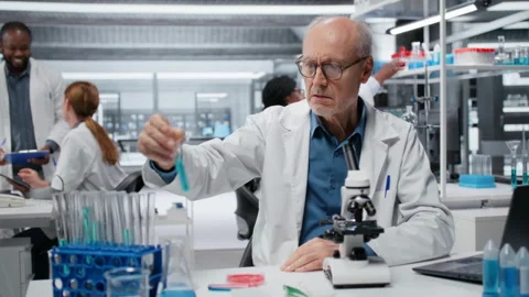 Upbeat elderly lab professional investigating blue liquid polymer properties Stock Footage 326703100