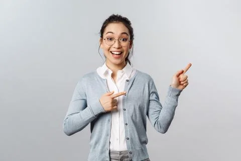 Upbeat excited mixed-race girl in glasses, asian woman teacher pointing fingers Stock Photos
