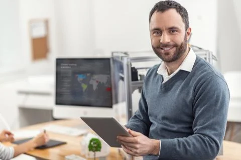 Upbeat man posing while reading from tablet Foto stock