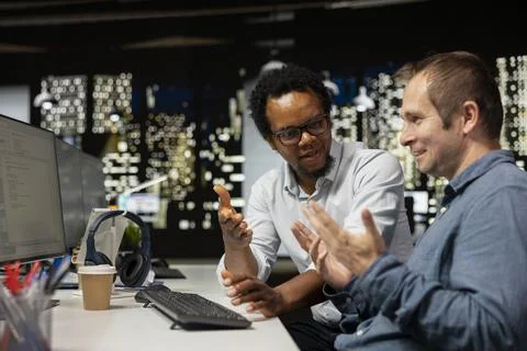 Upbeat programmers laughing, sharing jokes in startup office Stock-Fotos