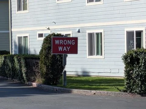 Upclose red wrong way sign with blue building and green grass Stock Photos