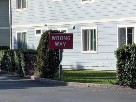 Upclose red wrong way sign with blue building and green grass Stock Photos