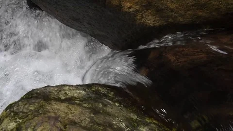 Upclose view of water flowing between 2 rocks in river Stock Footage