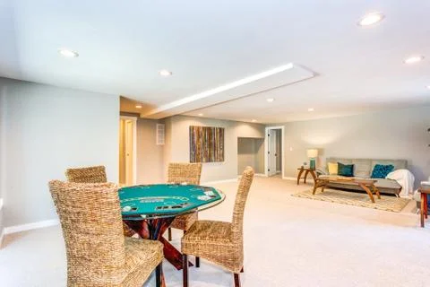 Updated home interior with spacious basement, poker table and wicker chairs. Stock Photos