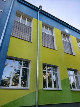 Updated school facade painted in blue yellow and green tones with modern re.. 스톡 사진