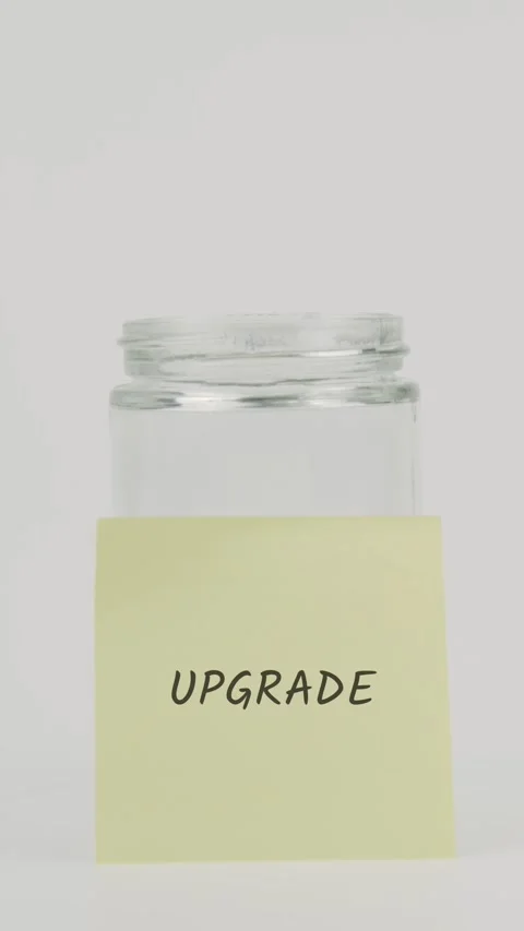 Upgrade text or word on yellow sticky note attached to glass jar with hand Stock Footage 311801329