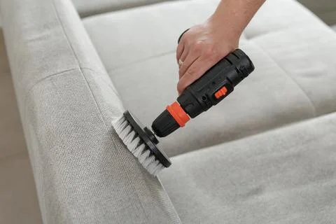 Upholstery cleaning with rotary brush tool on fabric sofa Stock Photos