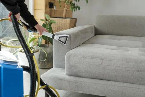 Upholstery cleaning of sofa armrest with extraction vacuum in home interior Stock Photos