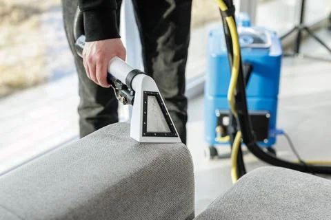 Upholstery cleaning of sofa armrest with extraction vacuum machine at home Stock Photos