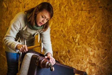 Upholstery workshop. An upholsterer using a hammer to secure fabric and padding Stock Photos