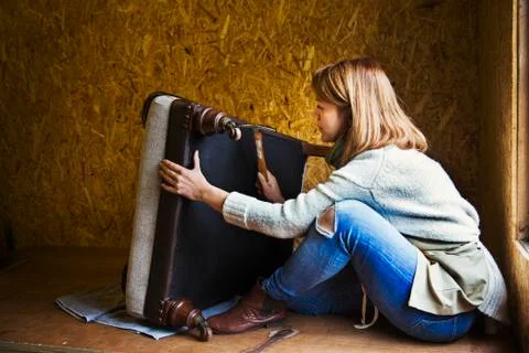 Upholstery workshop. An upholsterer working on the underside of a chair seat. Foto stock