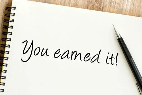Uplifting handwritten message You earned it on a notebook, celebrating acco.. Stock Photos