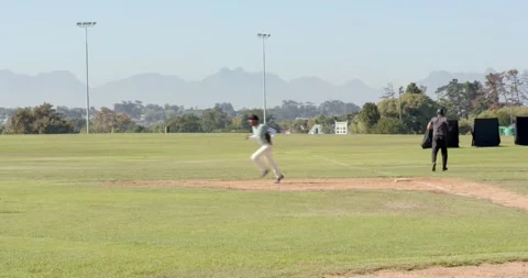 Upon batter hitting baseball, pitcher and diverse teammates gathering on mound Stock Footage 343238525
