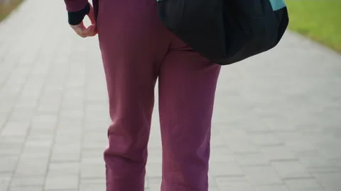 Upper Back View Gym Goer Walking on Gray Tiled Pavement with Bag on Shoulder Stock Footage 316642727