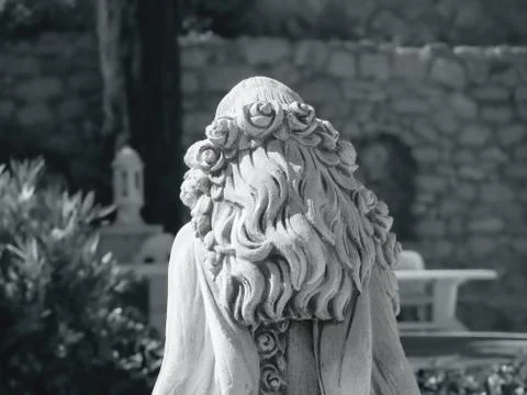 Upper back view of a white stone female statue, curly long hair Stock Photos