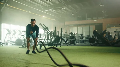 Upper cuts in combination with slams on battle rope done by athletic man in gym Stock Footage 239767812