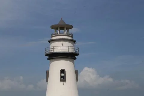The upper half of a lighthouse, painted white with black details, against a.. Stock Photos