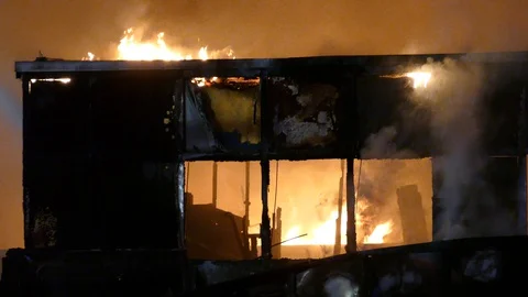 Upper part of building ripped opened and on fire glowing in the dark Video stock 129986843