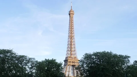 Upper part of Eiffel Tour above green trees crowns evening time in Paris Stock Footage 76350044