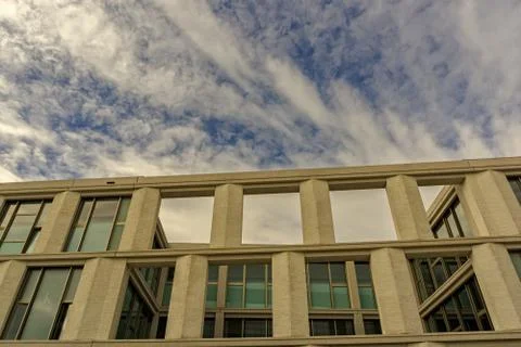 The upper part of a modern building below a cloudy summer sky Stock Photos