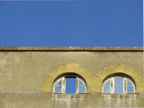 Upper part of an old building with one open and one closed window, background Stock Photos