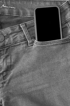 The upper part of old worn black jeans and a smartphone with a black screen Stock Photos