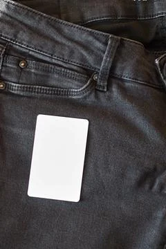 The upper part of old worn black jeans with pockets and a white tag for cloth Stock Photos