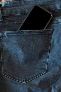 The upper part of old worn black jeans and a smartphone with a black screen Stock Photos
