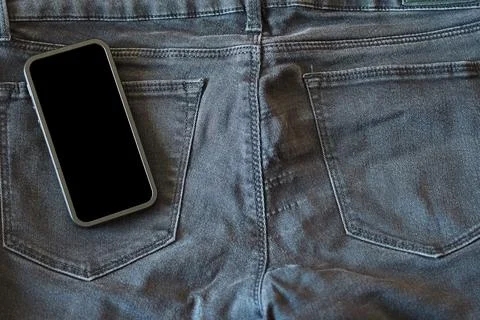 The upper part of old worn black jeans and a smartphone with a black screen Stock Photos
