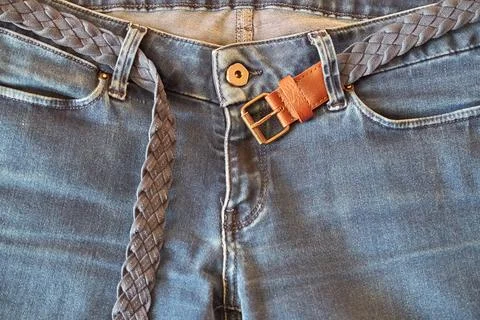 The upper part of old worn blue jeans with pockets and a braided belt Stock Photos