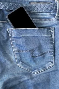 The upper part of old worn blue jeans and a smartphone with a black screen Foto stock