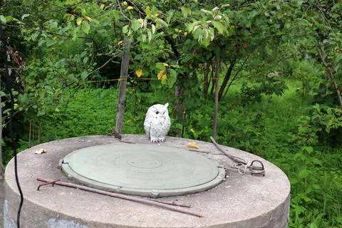 The upper part of a round stone well with decorative figurine of an owl Stock Photos