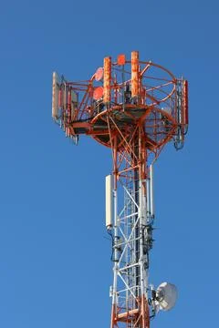 The upper portion of a telecommunications tower rising against a clear, Stock Photos