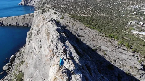 Upper round motion men stand on rock top against sea Video stock 103835850