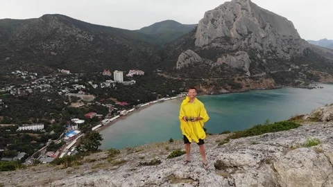 Upper view man stands on steep cliff top lifts drone camera Video stock 103180905