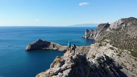 Upper view men on rocky cliff top surrounded by blue sea Video stock 103836363