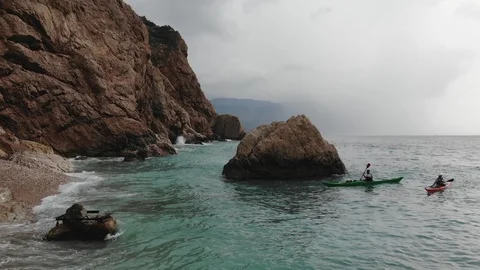 Upper view people in canoes sail near rock on endless sea Video stock 103182440