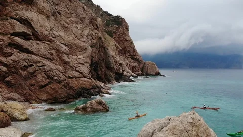 Upper view people on canoes sail on rough sea near cliff Video stock 103182629